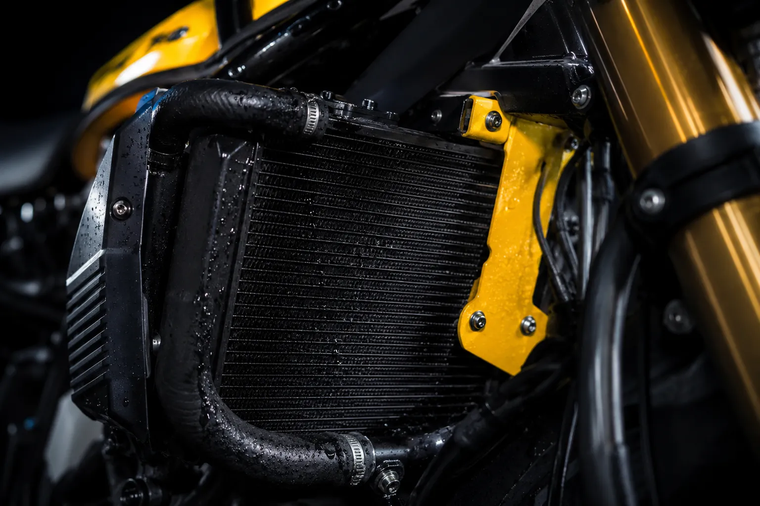 Radiador de moto en primer plano, amarillo y negro, sobre fondo oscuro